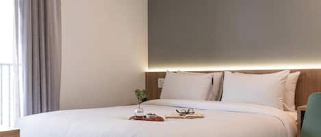 A neatly made bed with a tray of breakfast items, a book, and glasses on the bedside table.