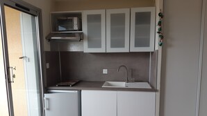 A compact kitchenette with a refrigerator, microwave, and sink. - 1-bedroom studio with sea view. Ideal for 2 adults and 1 child. (Saint Pierre la mer)