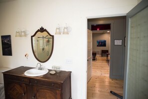 A bathroom with a wooden vanity, a large mirror, and a wall-mounted light fixture.