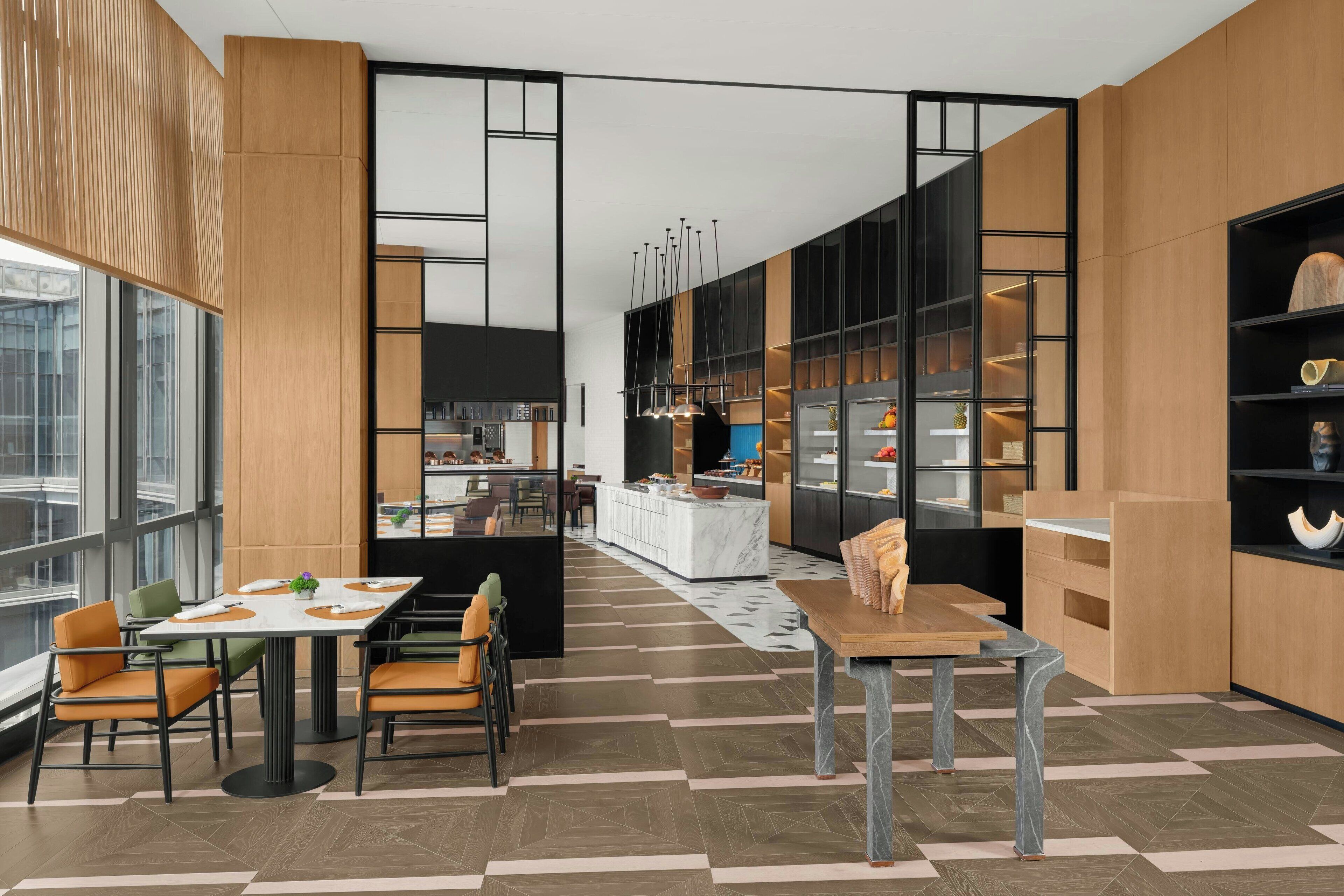 Une cuisine moderne dotée d’un îlot central, de meubles en bois et d’un coin repas avec des chaises orange.