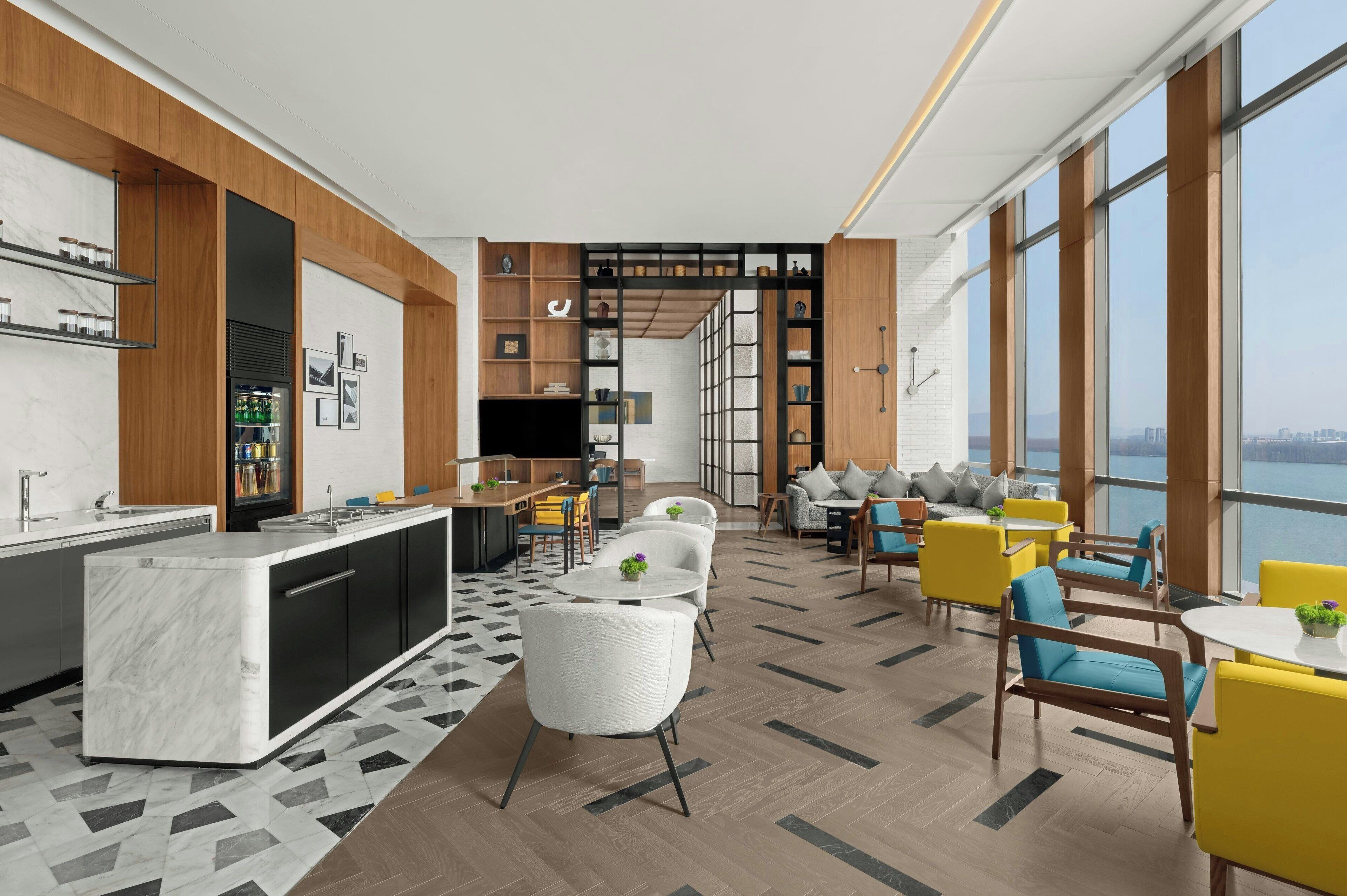 A modern hotel lobby with a marble bar, seating areas, and large windows offering a city view.