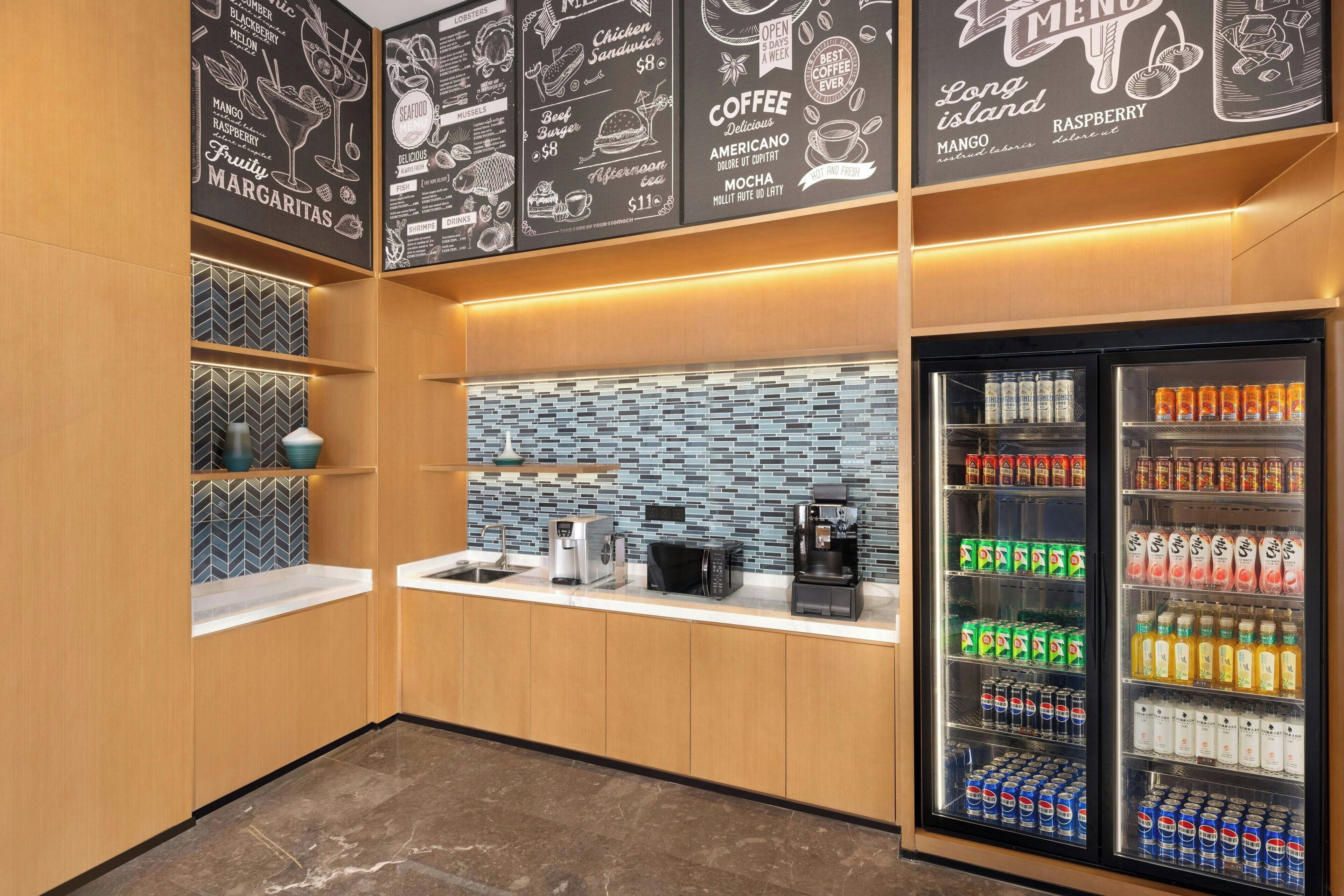 Un moderno café con un panel de menú, una máquina de café y un refrigerador lleno de bebidas.