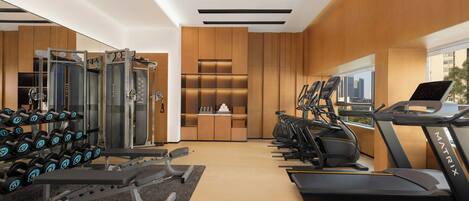 Un gimnasio moderno con cintas de correr, mancuernas y máquinas de pesas.