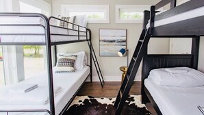 Une chambre avec un lit superposé, un tapis en peau de vache, une échelle et un tableau encadré au mur.
