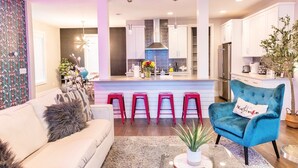 Une cuisine moderne avec des meubles blancs, un îlot central et des tabourets de bar rouges.