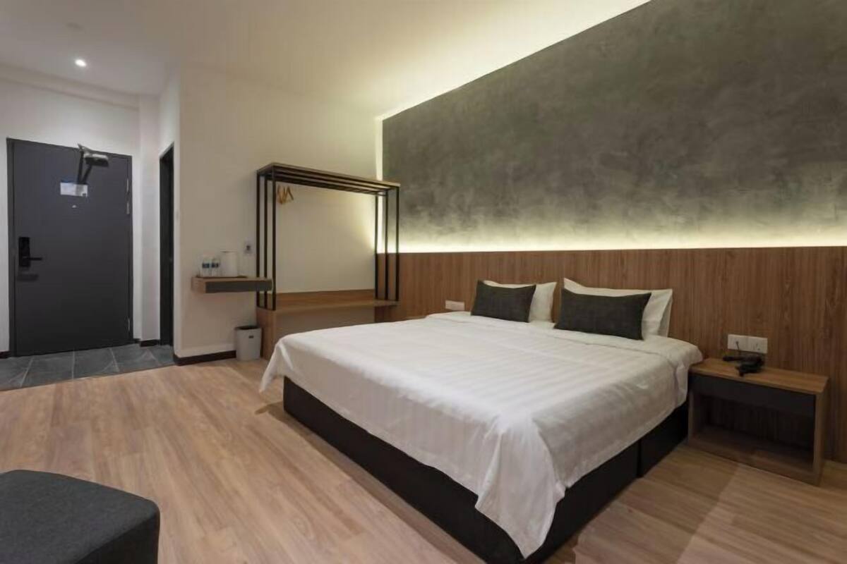 A modern bedroom with a large bed, wooden headboard, bedside tables, and a mirror.