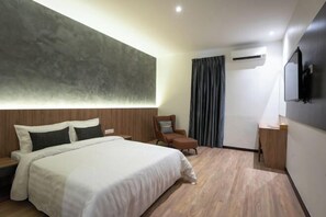 A modern hotel room with a large bed, a wooden headboard, a flat-screen TV, and a built-in air conditioning unit. - Blu Sentral Hotel (Tawau)