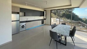 Eine moderne Küche mit integrierten Geräten und einem Essbereich mit großem Tisch und Stühlen.