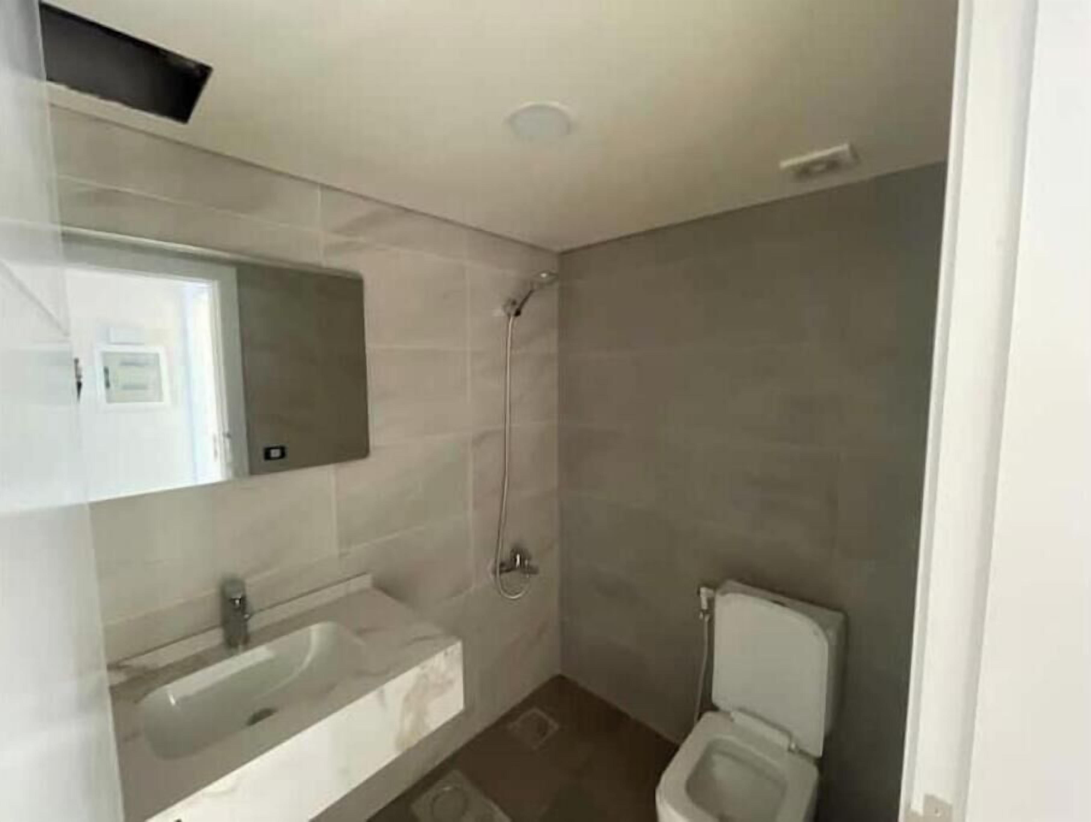 Un baño con lavamanos, espejo, ducha e inodoro.