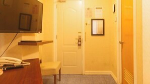 A hotel room with a wooden desk, a telephone, a chair, a door, and a wall-mounted mirror. - RedDoorz at Emperor Manila Boutique Hotel (City of Manila)