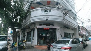 A building with a curved facade, a 'WELCOME' sign, and parked cars. - RedDoorz at Emperor Manila Boutique Hotel (City of Manila)