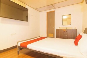 A bedroom with a bed, a wooden wardrobe, a mirror, and a television mounted on the wall. - RedDoorz at Emperor Manila Boutique Hotel (City of Manila)