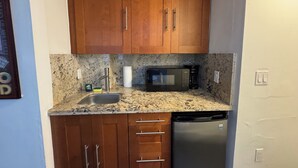 A compact kitchen with wooden cabinets, a stainless steel sink, a microwave, and a dishwasher. - Lovely studio 3 Minute Walk to Miami Beach (Miami Beach)