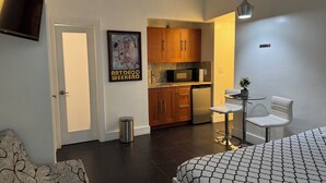 A compact hotel room with a kitchenette, a small dining area, and a bed with patterned bedding. - Lovely studio 3 Minute Walk to Miami Beach (Miami Beach)