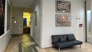 A hallway with a black leather sofa, a staircase, and two framed pictures of buildings. - Lovely studio 3 Minute Walk to Miami Beach (Miami Beach)