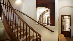 A wooden staircase with a handrail, a white wall, and a door with glass panels. - Gîtes de France® - Gîte du Chateau Saint Didier (PARNAC)