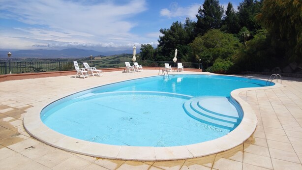 A swimming pool with a tiled deck, surrounded by white lounge chairs and umbrellas. - Panorama Residence swimming pool 2 bedrooms (San Giovanni)