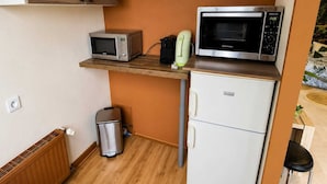 Uma cozinha compacta equipada com micro-ondas, torradeira e pequeno frigorífico.