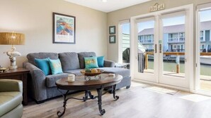 A living room with a gray sofa, a wooden coffee table, and a ceiling fan. - Waterfront Luxury Condo (Rockport)