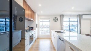 Une cuisine moderne dotée d’un îlot central, de meubles en bois et d’une grande fenêtre qui laisse entrer la lumière naturelle.
