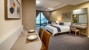 A hotel room with a bed, a desk, a dining table set for two, and a large window with a view. - Sunway Sanctuary - Seniors Hotel & Residences (Subang Jaya)