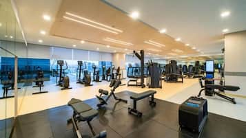 A gym with various exercise equipment, a mirrored wall, and a large window.