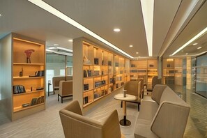 Una biblioteca moderna con estanterías, asientos cómodos y un muro de vidrio.