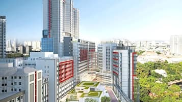 Un quartier urbain moderne, avec de hauts immeubles, une cour centrale agrémentée de verdure et un pont piétonnier.