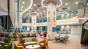 A spacious lobby with a central seating area, a staircase, and a high ceiling with circular lighting. - Sunway Sanctuary - Seniors Hotel & Residences (Subang Jaya)