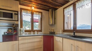 A kitchen with wooden cabinets, a stainless steel range hood, a microwave, and a sink. - CHALET LE TREDARD - FEISSONS SUR SALINS (FEISSONS SUR SALINS)