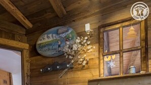 A rustic wooden interior with a white dresser, a decorative plate, and a window with a view. - CHALET LE TREDARD - FEISSONS SUR SALINS (FEISSONS SUR SALINS)