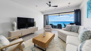 A modern living room with a flat-screen TV, wooden coffee table, and a sofa. - Allure 502. A stunning 2 Bedroom Beachfront Condo
with Breathtaking Ocean Views (St. Michael)