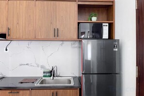 Eine Küche mit Holzschränken, einem Edelstahl-Kühlschrank, einer Mikrowelle und einer Marmor-Spritzschutzwand.