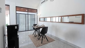 A modern room with a dining table, chairs, a TV, and a large window. - The Lavana De Mello Villa Seminyak (1 Bedroom Villa with Private Pool) (Bali)
