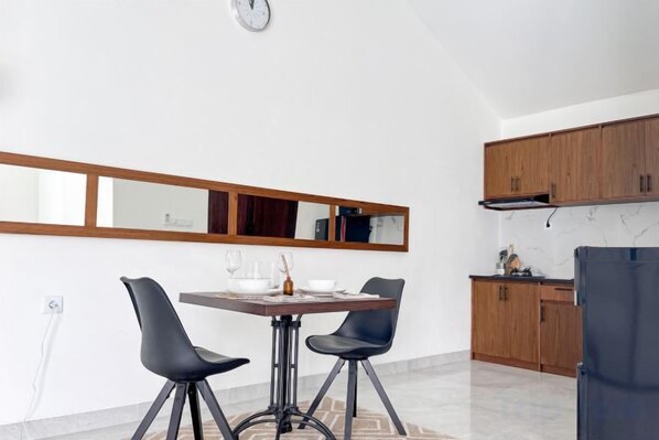Eine moderne Küche mit Holzausziehtischen, einem Esstisch mit zwei Stühlen und einem großen Spiegel darüber.