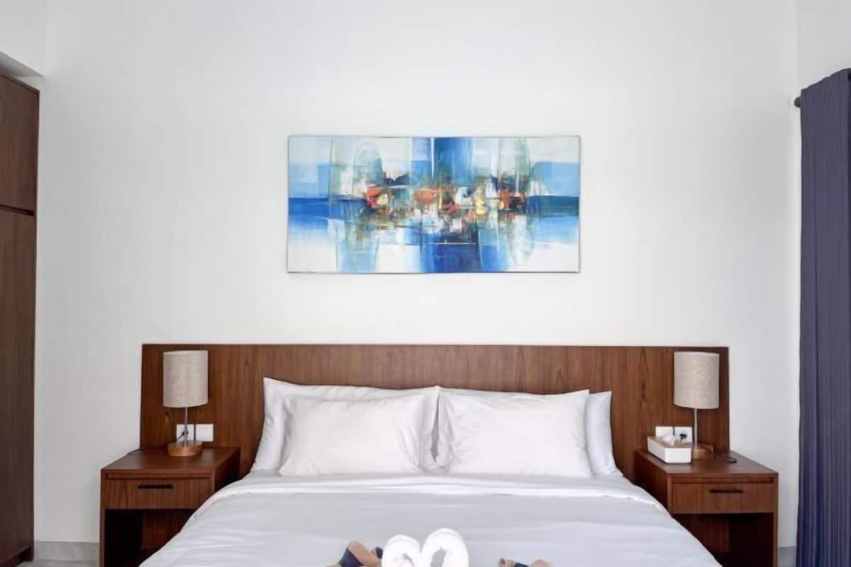 Une chambre d’hôtel avec un grand lit, deux tables de chevet et un tableau accroché au mur.