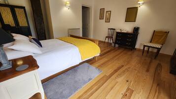 A bedroom with a bed, bedside table, dresser, chair, and a desk with a lamp.