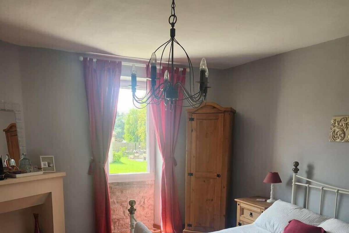 Un dormitorio con una cama, un armario de madera, un escritorio y una ventana con cortinas.