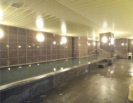 Piso mojado en un espacio público interior con paredes de baldosas y una partición de vidrio.