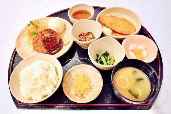 A tray with various Japanese dishes including rice, soup, and a fish cake.