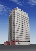 Un edificio alto de varios pisos con fachada plana, numerosas ventanas y un letrero con información de contacto en la parte superior.