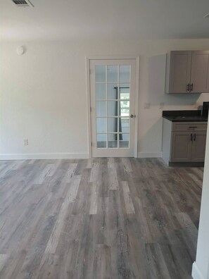 A room with a wooden floor, a white door with glass panels, and light-colored cabinets. - Cozy 6-Person Cottage Near I-75 (Sumner)