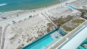 Une plage avec vue sur la mer, une piscine, des zones de sable et quelques personnes.