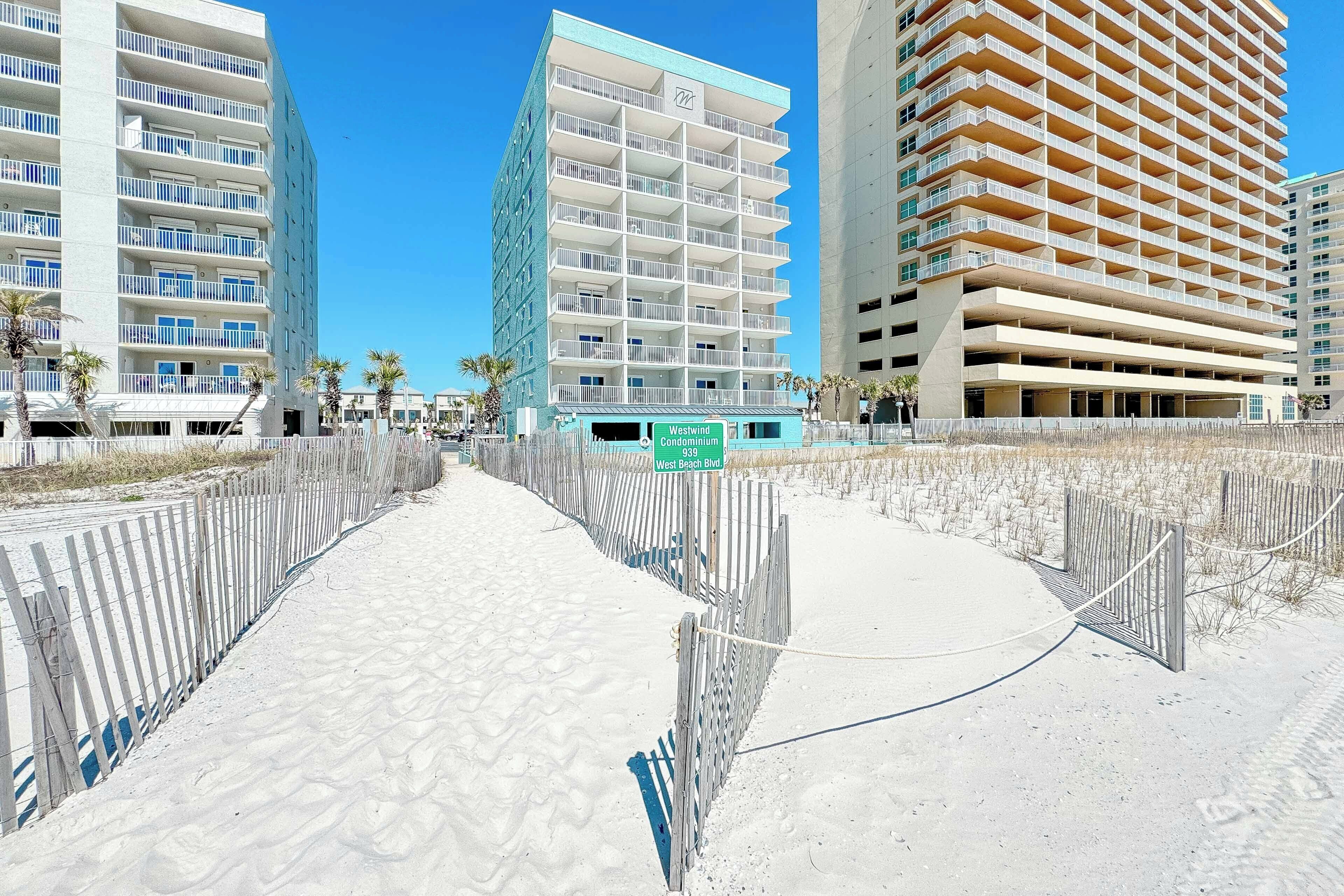 Un hôtel situé en bord de mer, avec plusieurs étages, des balcons et une promenade piétonne de sable.