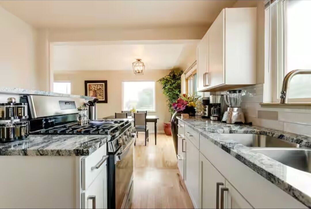 A modern kitchen with a central island, stainless steel appliances, and a view to the dining area.