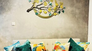 En stue med en beige sofa og farverige blomstermønstrede puder.