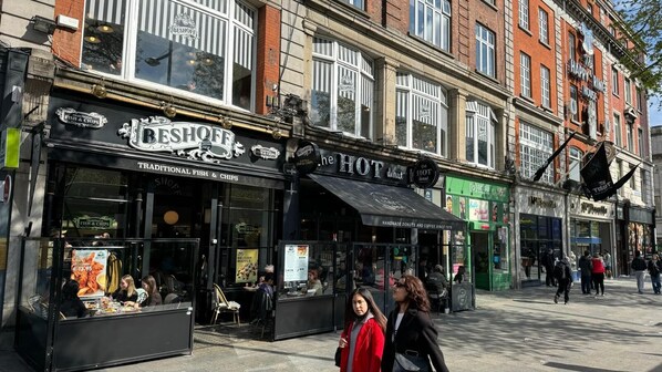 A street with various shops including a fish & chips restaurant and a hot donut shop.