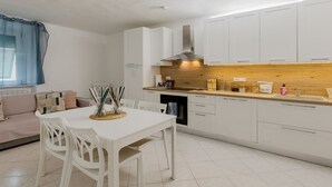A modern kitchen with white cabinets, a wooden countertop, and a dining area with white chairs.
