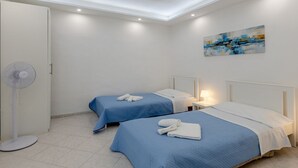 A hotel room with two beds, a ceiling fan, a painting, and a tiled floor.