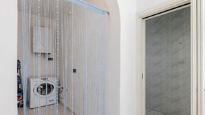 A bathroom with a shower, a washing machine, and a tiled floor.